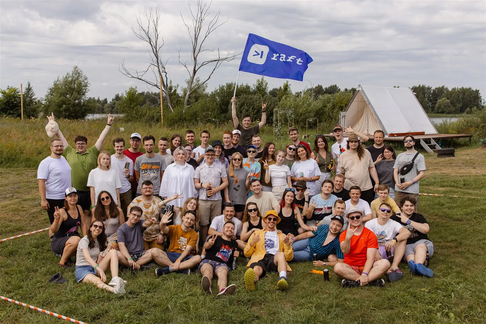 Команда Raft на выездном мероприятии, с флагом компании